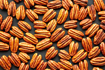 Homemade Shelled Pecans in a bowl on a black background, top view. Flat lay, overhead, from above.
