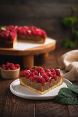 Tart with pistachio and raspberries on shortcrust pastry. Delicious pie with fresh berries on a wooden table.