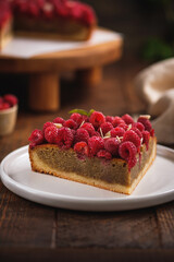 Tart with pistachio and raspberries on shortcrust pastry. Delicious pie with fresh berries on a wooden table.