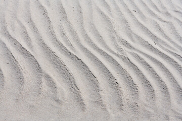 Różne formy piasku na morskiej plaży ukształtowane przez fale i wiatr.