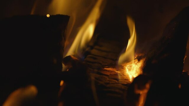 Fireplace, flames over wooden logs. Cozy fire. Close up, Macro. Burning firewood. Filmed in RAW 120fps 4K