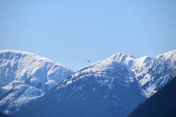 plane flying in over snow capped mountains
