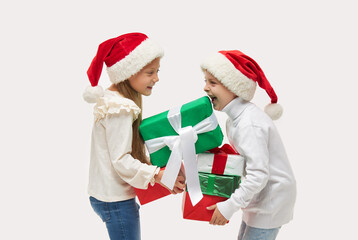 Christmas child. Cute toddler girl abd boy in santa claus caps holding high stack of colorful gift boxes and laughing on white background