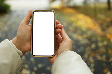 Phone with an isolated screen in hands on the street in the autumn park