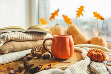 Autumn still life on the windowsill, a cup of tea, candles, pumpkins, leaves, thanksgiving house interior
