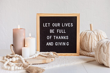 Felt letter board and text let our lives be full of thanks and giving. Autumn table decoration. Interior decor for thanksgiving and fall holidays with handmade pumpkins and candles