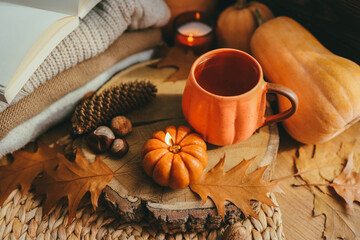 A cup of tea in the shape of a pumpkin and autumn decor on the windowsill, aesthetic photo.