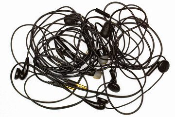 Old tangled headphones on a white background. Isolated. Black dusty dirty wired headphones with...