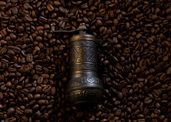 Old coffee grinder with coffee beans in the background