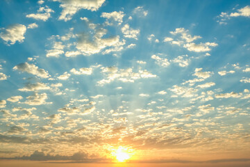 Blue sky with twilight clouds. The sun is setting over the horizon. Yellow dawn. Red sunset. Pink clouds.