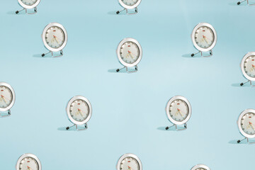 Sunlight summer pattern made with white vintage clock on bright blue background. Conceptual photo. Minimal time concept.