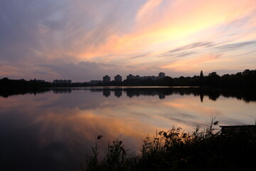 Naklejka premium Scenic sunrise by the lake with morning fog. Pastel colors of sky, mist above the water and dark silhouette of trees. Magic, moody landscape of a dawn.