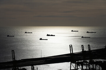 Many cargo ships waiting near port of Barcelona during sunset. Transportation and industry concept