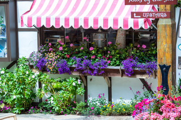 Fototapeta na wymiar California, 07/11/2011: Quaint ivy covered shops with flowers and striped awning in Carmel by the sea, city on the Pacific coast known for its enchanting architecture.
