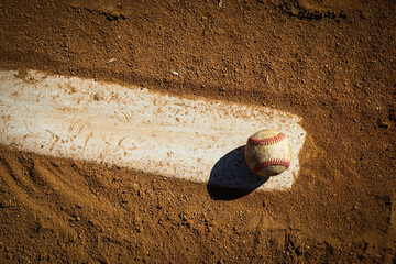 Baseball on pitcher's mound rubber on dirt field