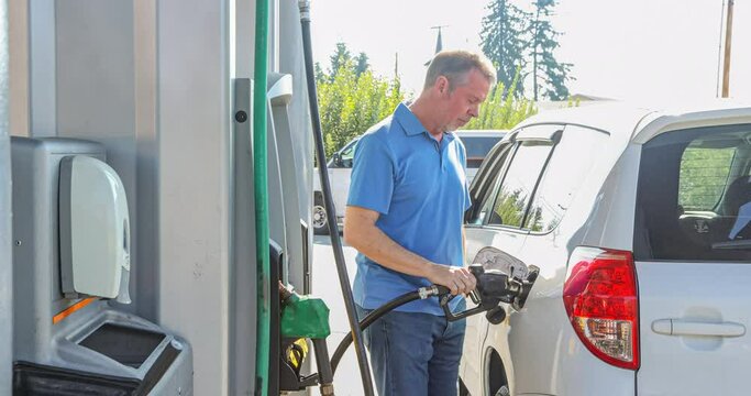 Adult male at a gas station filling the tank of his SUV, distraught by the inflated cost of petrol