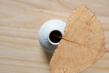 autumn leaf in a white vase on wood