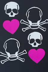 skull and crossbones with pink hearts on black paper
