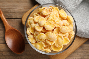 Bowl of tasty corn flakes on wooden table, flat lay