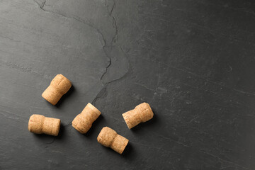 Fototapeta na wymiar Sparkling wine corks on black table, flat lay. Space for text