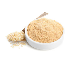 Sesame flour in ceramic bowl and spoon of seeds isolated on white