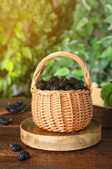 Fototapeta na wymiar Fresh ripe black mulberries on wooden table against blurred background