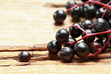 Black elderberries (Sambucus) on wooden table, closeup. Space for text