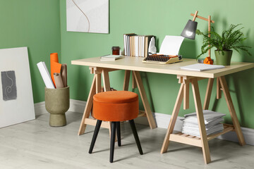 Writer's workplace with typewriter on wooden desk near pale green wall in room