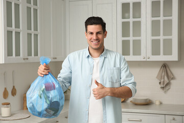 Man holding full garbage bag at home