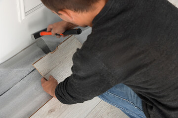 Worker installing new laminate flooring in room, closeup