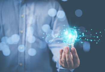 Innovation technology brainstorming to the future on black background. Business, inspiration, and innovation concept. Businessman holding a bright illuminated light bulb on hand with copy space.