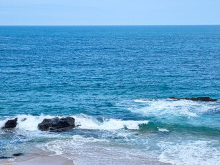 Mar calmo com ondas quebrando nas pedras