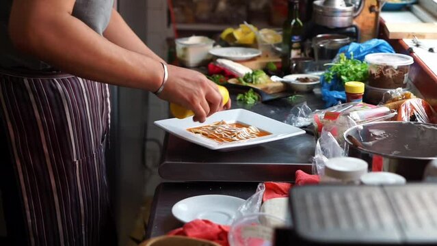 Close up of a chef putting cream and lettuce on enchiladas in a Mexican restaurant.