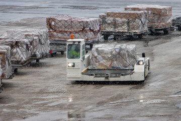 A vehicle loaded with air cargo is driving on a snowy airport