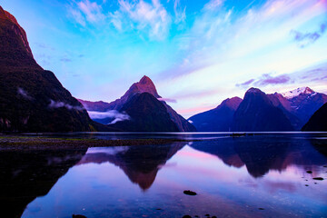 Fototapeta na wymiar Mitre Peak and other mountain reflections at Milford sound at dawn