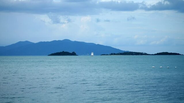Beautiful tropical beach with blue sky and white cloud, mountains background. Sailing boats on the blue sea. Summer vacation. Nature environment concept. Tourism and travel
