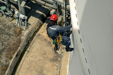 Male worker rope access height safety inspection of thickness storage tank