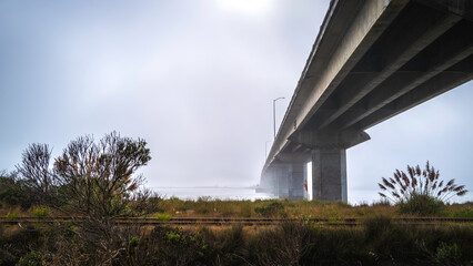 Dramatic cloudscape at sunrise over the railway and Samoa Bridge on a foggy morning on State Route 255 over Arcata Bay near Eureka, California
