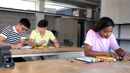 Multiracial teen high school students in electronics class working on a project. Handheld 4k video.