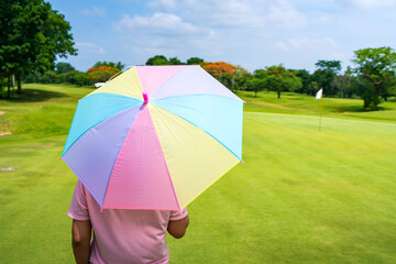 women Golfers under umbrella on green grass at golf course