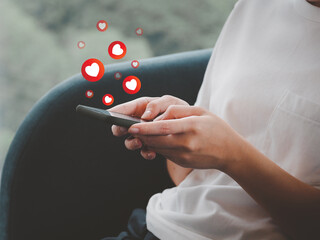 Social media and online digital concepts A young woman using a smartphone, pressing the heart,...