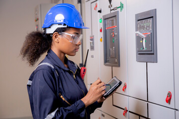Electrical young asian woman engineer examining maintenance cabinet system electric and using...