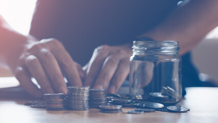 Stack coins on wood table, money saving concept. Man counting the coin and stacking.