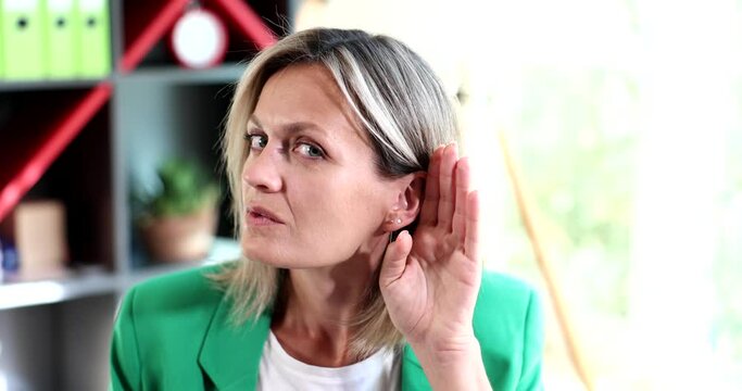 Woman put her hand to her ear and listened carefully in office