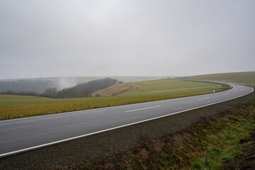 Long rural asphalt road in the landscape on a foggy morning in december 