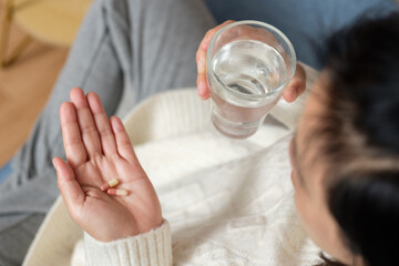 asian woman taking pill when get sick at home