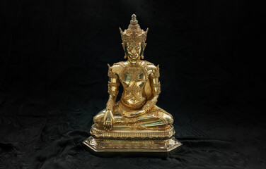 Obraz premium Figurine of Gold Brass Phra Phut Sik Khi Thotsaphon (First Buddha) buddha sculpture statue with dark background. Space for text, Selective focus.