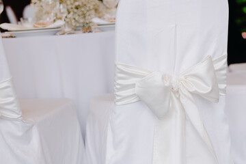 Chair cover with white ribbon tied with a bow at a wedding