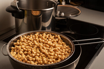 Chickpeas in a colander next to a pot on the kitchen counter,close-up