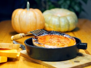 Homemade healthy food. Pumpkin baked in the kitchen oven in a frying pan on a wooden table.